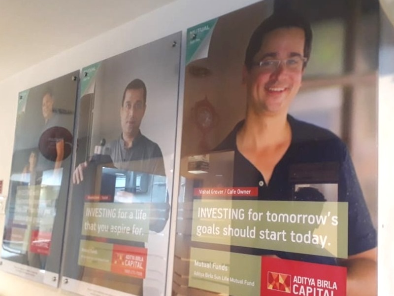 Wall-mounted acrylic sandwich brand frames on stainless steel studs for Aditya Birla Sun Life Mutual Fund